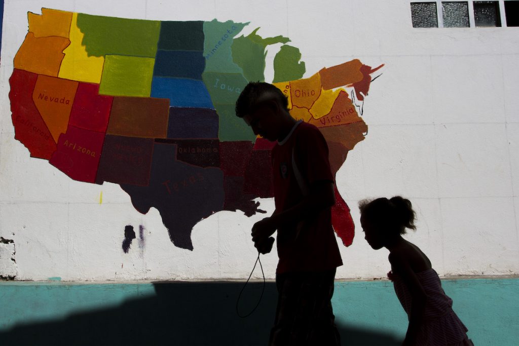 Image shows a father and daughter walking past a painted map of the United States